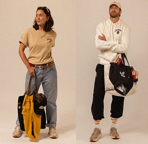 Two individuals in casual attire posing with bags, against a neutral backdrop.