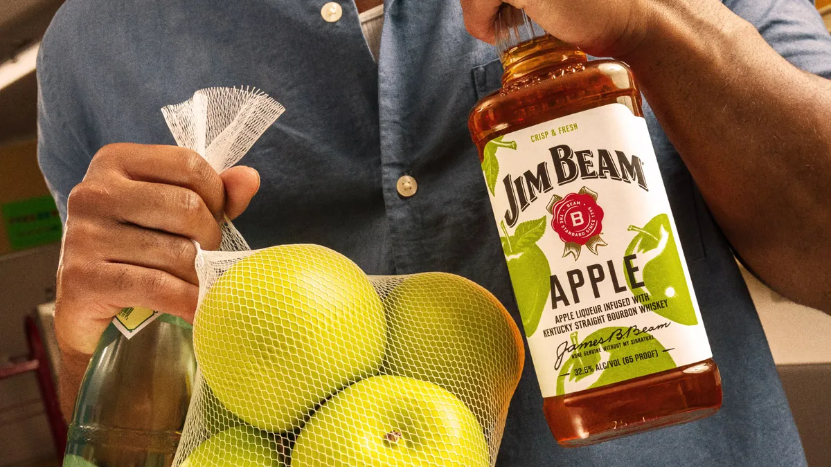 Man holding bag of apples and bottle of Jim Beam Apple