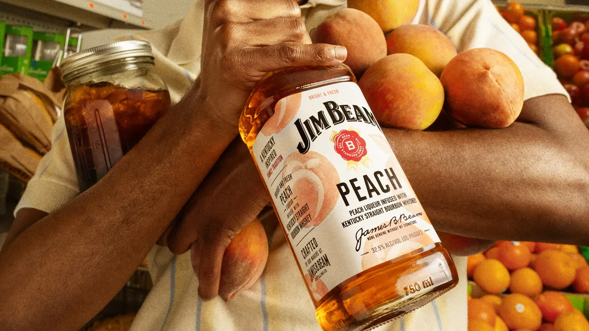 Man holding bunch of peaches and Jim beam Peach bottle