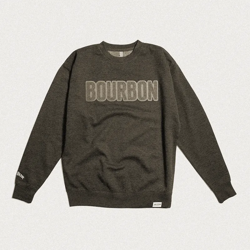 Dark sweatshirt with the word "BOURBON" on the front, displayed on a patterned beige background.