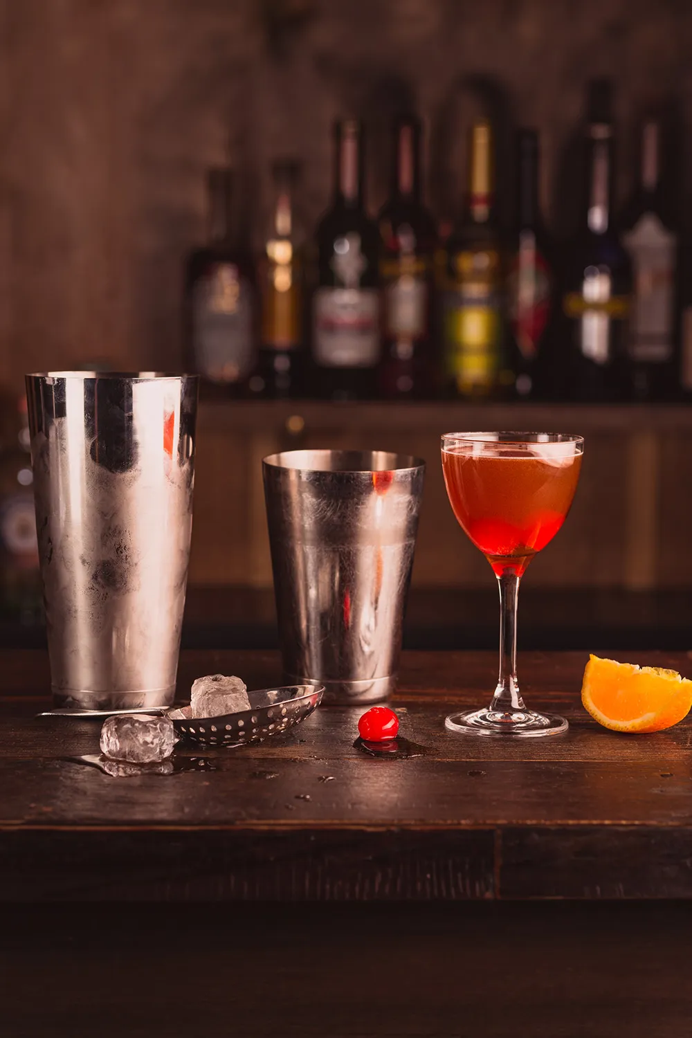 Jim Beam Bourbon Manhattan on the rocks with ice and a cherry garnish, isolated on a dark background.