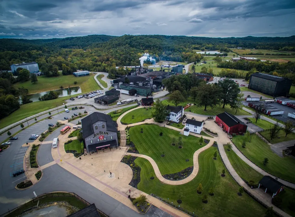 erial view of the Jim Beam Distillery campus surrounded by rolling hills and lush green landscape.